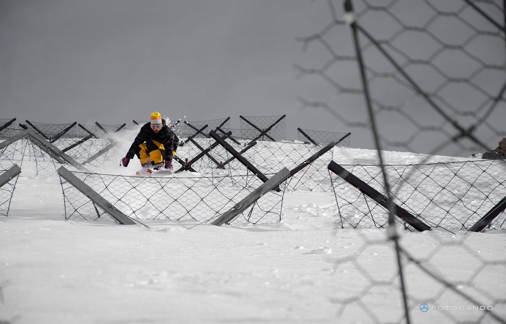 Snowboarder riding down between avalanche barriers