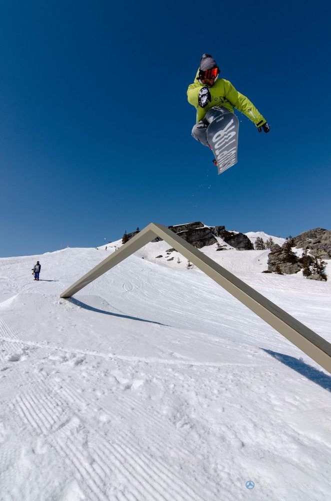 Snowboarder flying over the rail against a blue sky