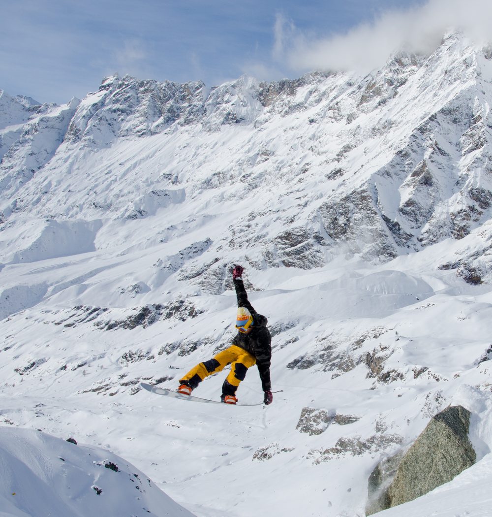 Snowboarder jumping between rocks and fresh snow