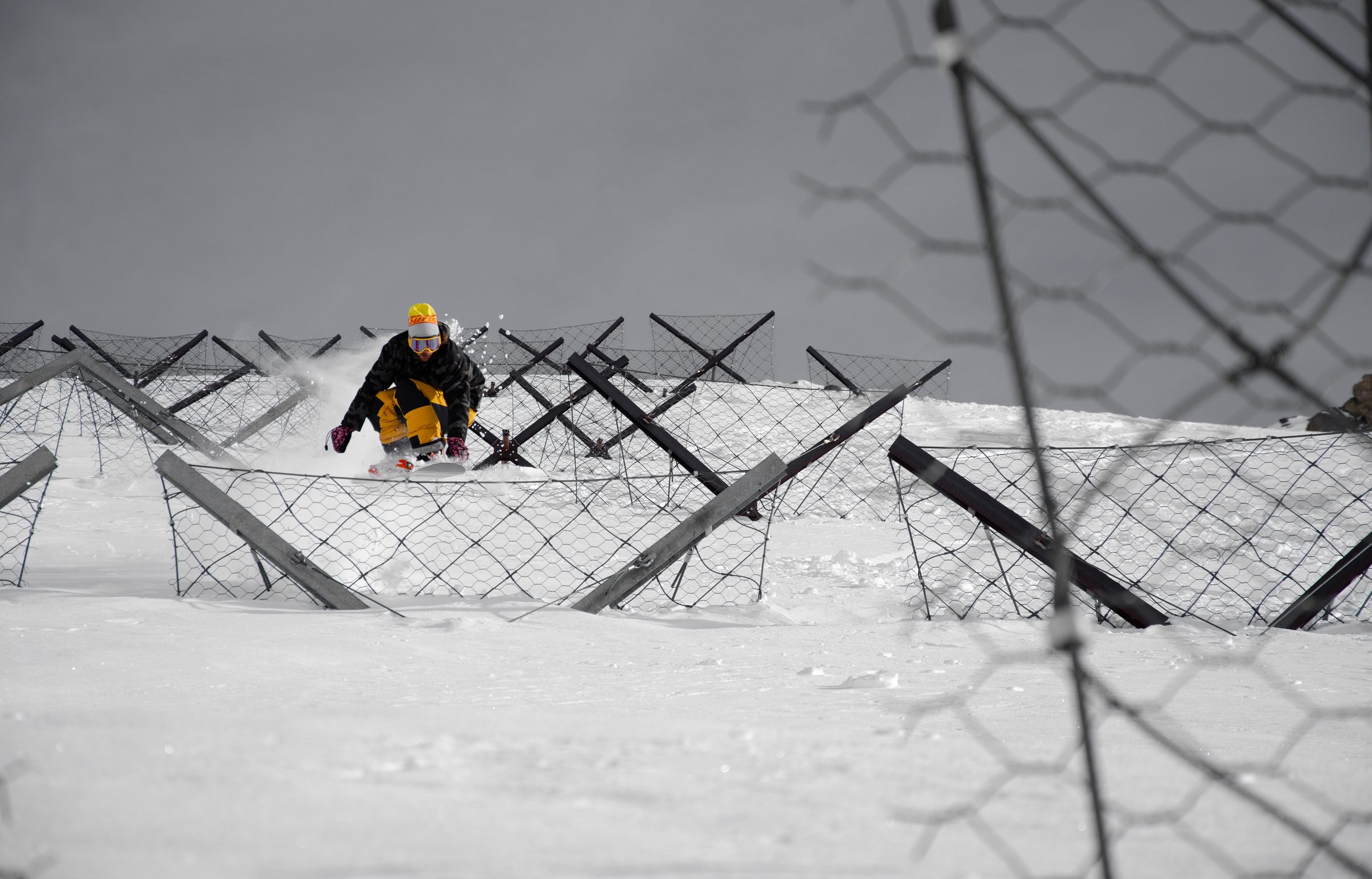 Snowboarder riding down between avalanche barriers