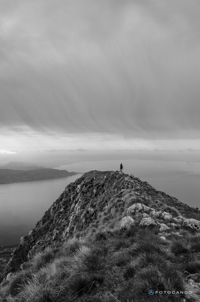 Hiker on top of a ridge above the lake, in black and white
