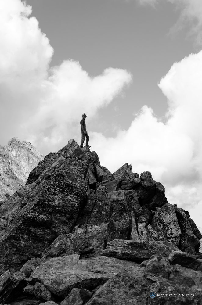 Hiker standing on top of a rock spur, in black and white, August 2018